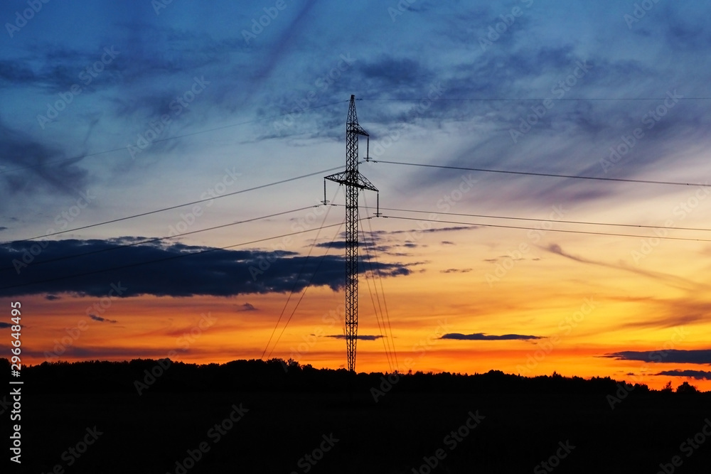 High voltage transmission power lines at sunset. Industrial evening landscape against the sky.