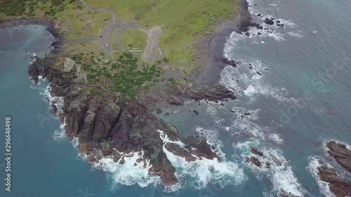 Flyover of rocky shoreline meeting Aorangi Ranges in New Zealands North Island photo