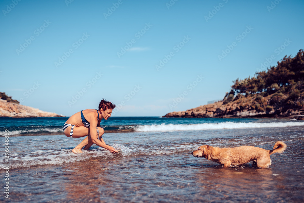 Woman paying with a dog on the beach