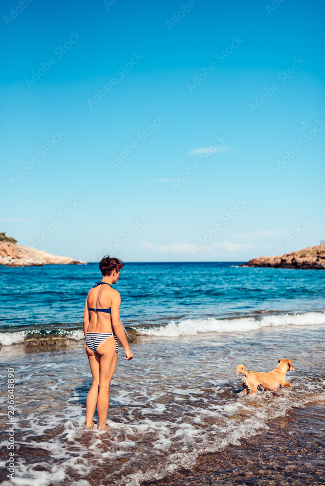 Woman paying with a dog on the beach