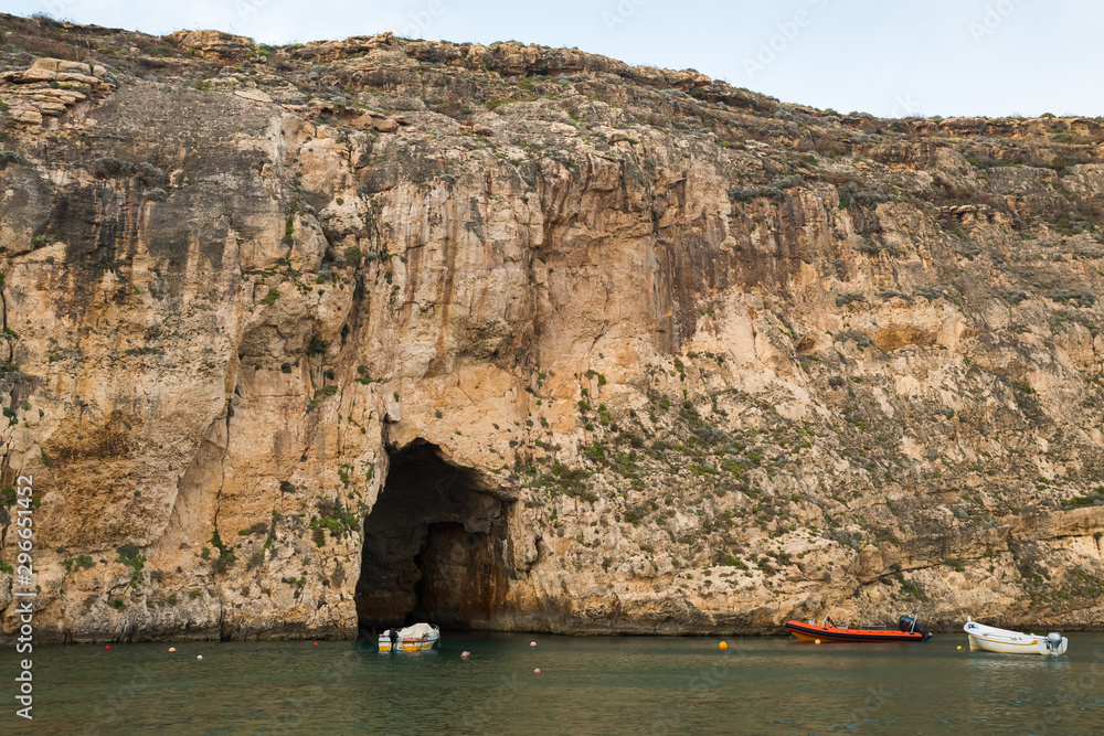 A Peaceful Bay, a Beautiful Cave and Three Boats Parked Nearby at Dusk