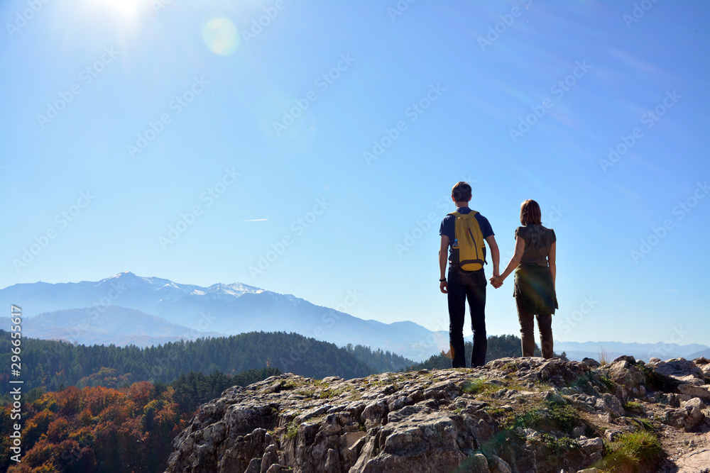 A couple on top of a mountain looks into the distance, Romania
