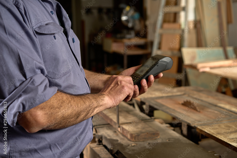 Man with blue overalls in carpentry using credit card. bank payment Man with blue overalls in carpentry using credit card. bank payment