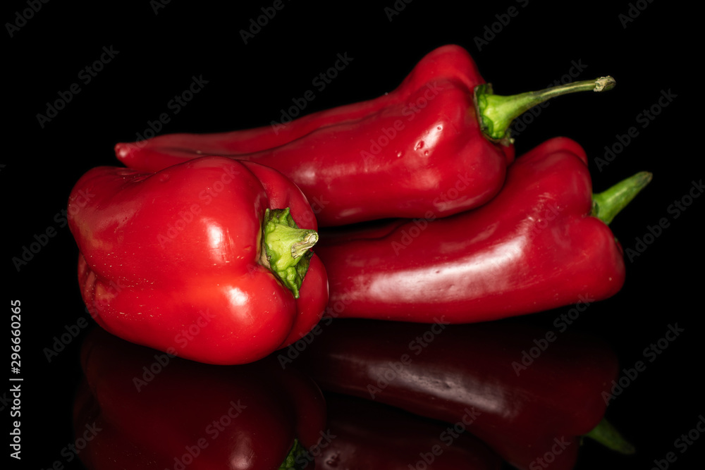 Group of three whole sweet red bell pepper isolated on black glass