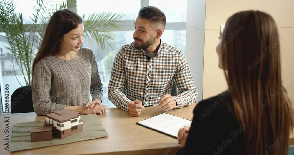 Happy married couple signing documents in real estate office, deciding to by house Happy married couple signing documents in real estate office, deciding to by house