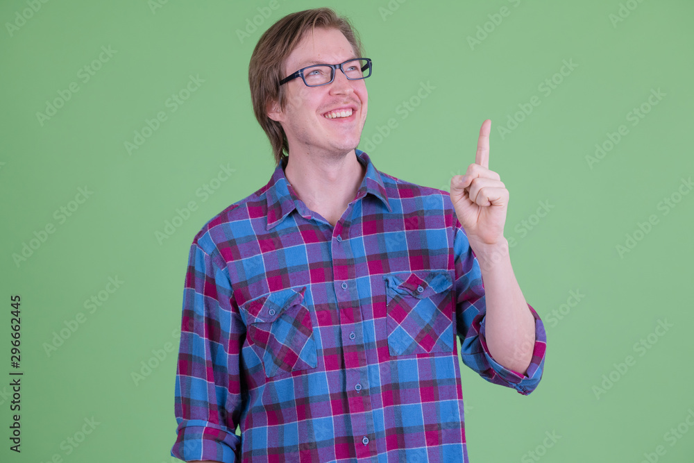 Happy young handsome hipster man thinking and pointing up Happy young handsome hipster man thinking and pointing up