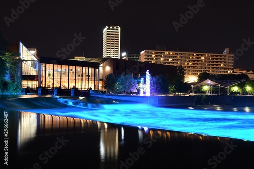 Panoramic view of downtown South Bend Indiana at night with the St Joseph river in the foreground, Century Center in the background and the St Joseph river lights on.