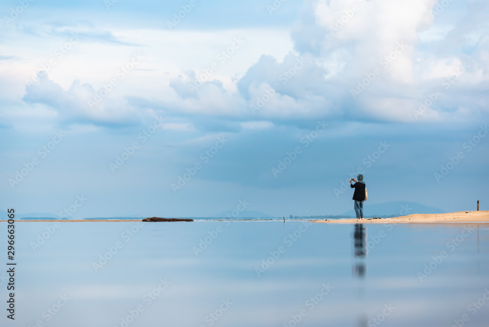 An Asian Muslim woman wearing a hijab standing on the beach and reflecting An Asian Muslim woman wearing a hijab standing on the beach and reflecting