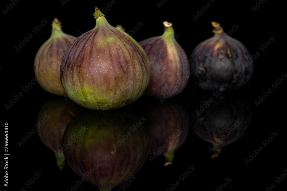 Group of four whole sweet purple fig isolated on black glass Group of four whole sweet purple fig isolated on black glass