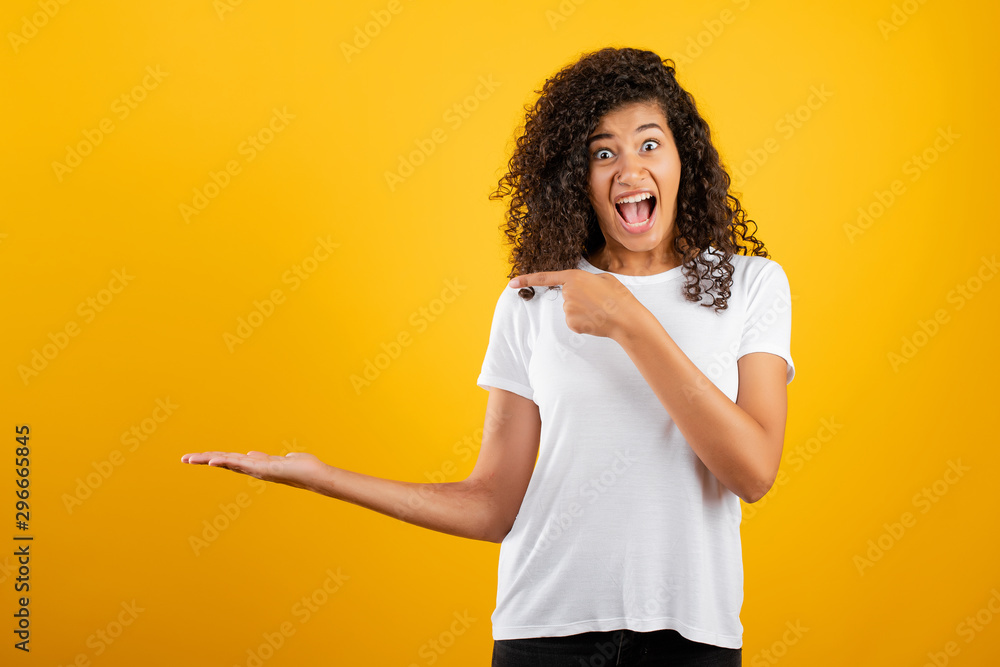 excited african black woman pointing finger at copyspace at hand isolated over yellow excited african black woman pointing finger at copyspace at hand isolated over yellow