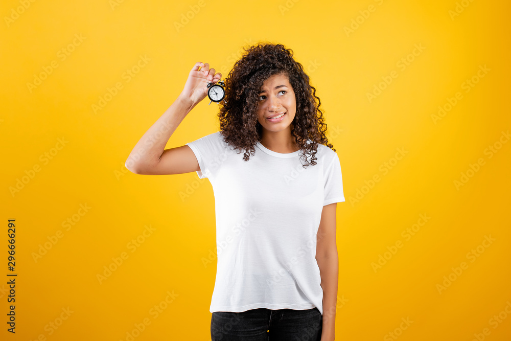 pretty african black girl with alarm clock isolated over yellow pretty african black girl with alarm clock isolated over yellow