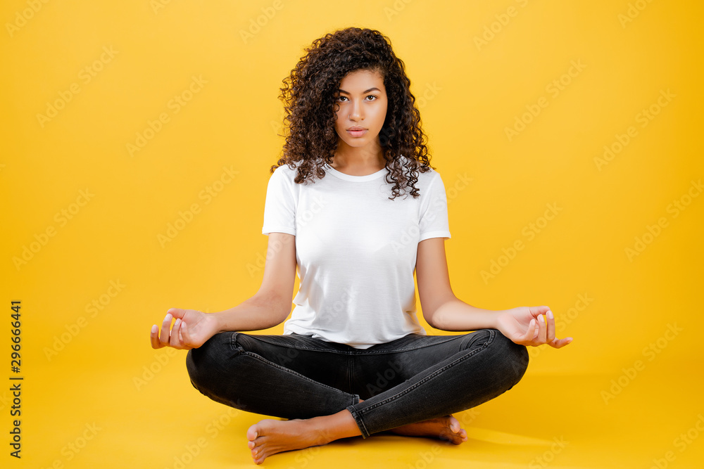 relaxed black woman meditating in yoga pose isolated over yellow relaxed black woman meditating in yoga pose isolated over yellow