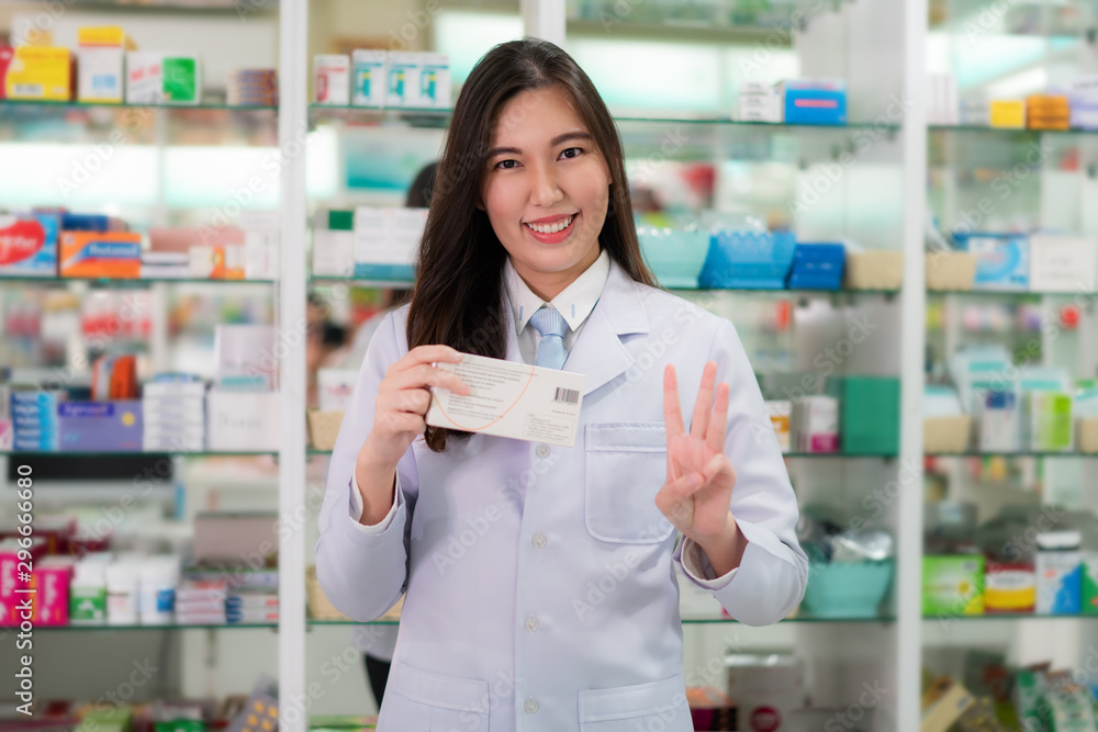 Asian young female pharmacist showing three finger explaining to her customer take a medicine three time or three capsule per day in the pharmacy drugstore. Medicine, pharmaceutics, health care