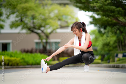Asian beautiful woman exercising stretch alone in public park in village, happy and smile in morning during sunlight. Sport fitness model Asian ethnicity training outdoor concept..