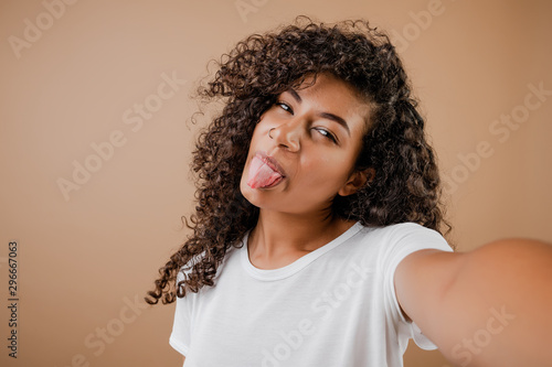lovely happy black young woman making selfie isolated over brown