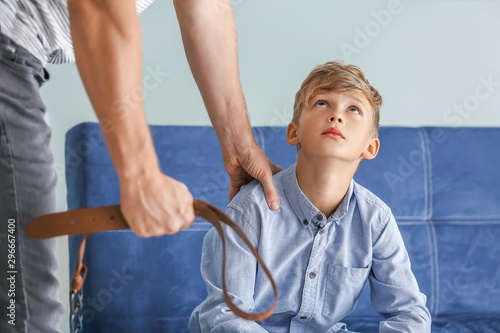 Man threatening his little son at home. Physical punishment concept photo