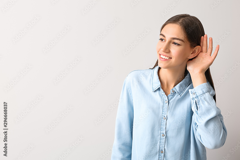 Young woman with hearing problem on light background Young woman with hearing problem on light background