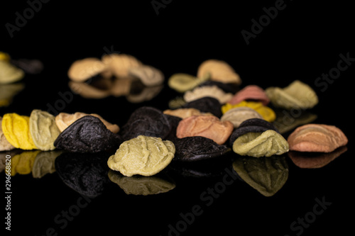 Lot of whole disordered colorful pasta orecchiette isolated on black glass © PIXbank