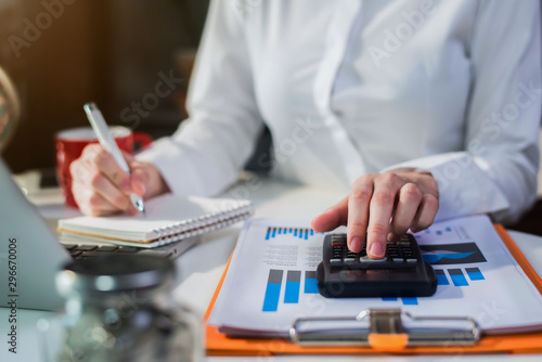 Female businessman working on desk office with using a calculator to calculate the numbers, finance accounting concept.