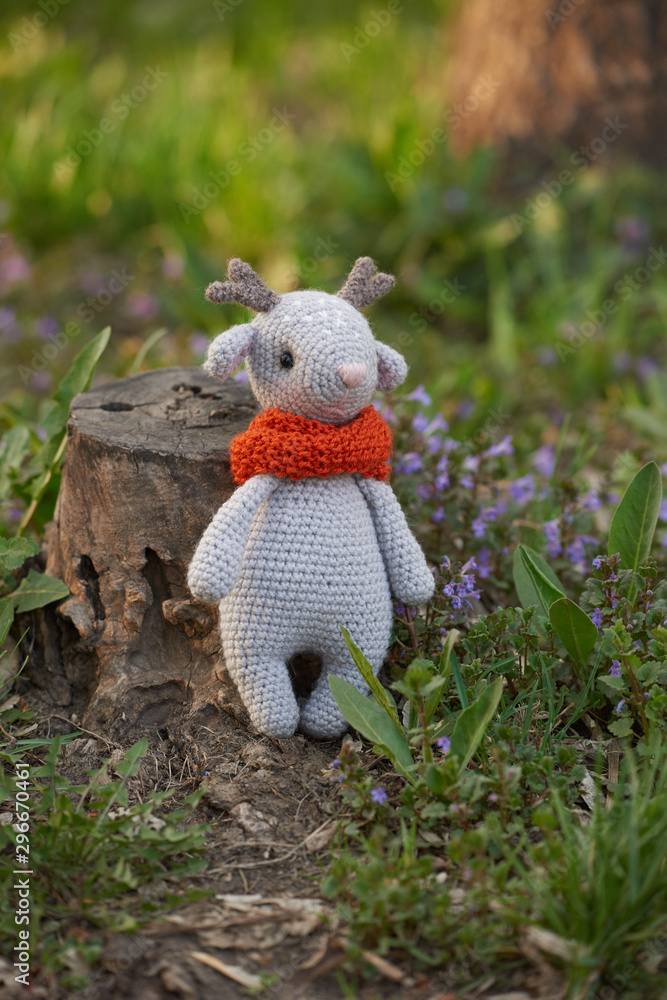 Beautiful handmade soft toy fawn. Outdoor photography, grass and a small stump. Beautiful handmade soft toy fawn. Outdoor photography, grass and a small stump.