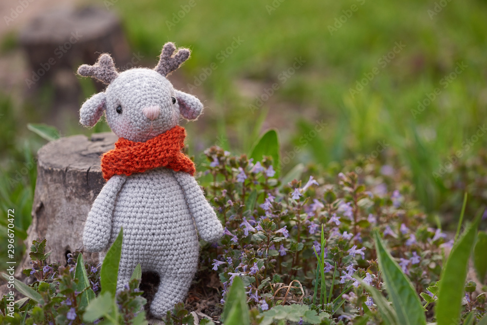 Beautiful handmade soft toy fawn. Outdoor photography, grass and a small stump. Beautiful handmade soft toy fawn. Outdoor photography, grass and a small stump.