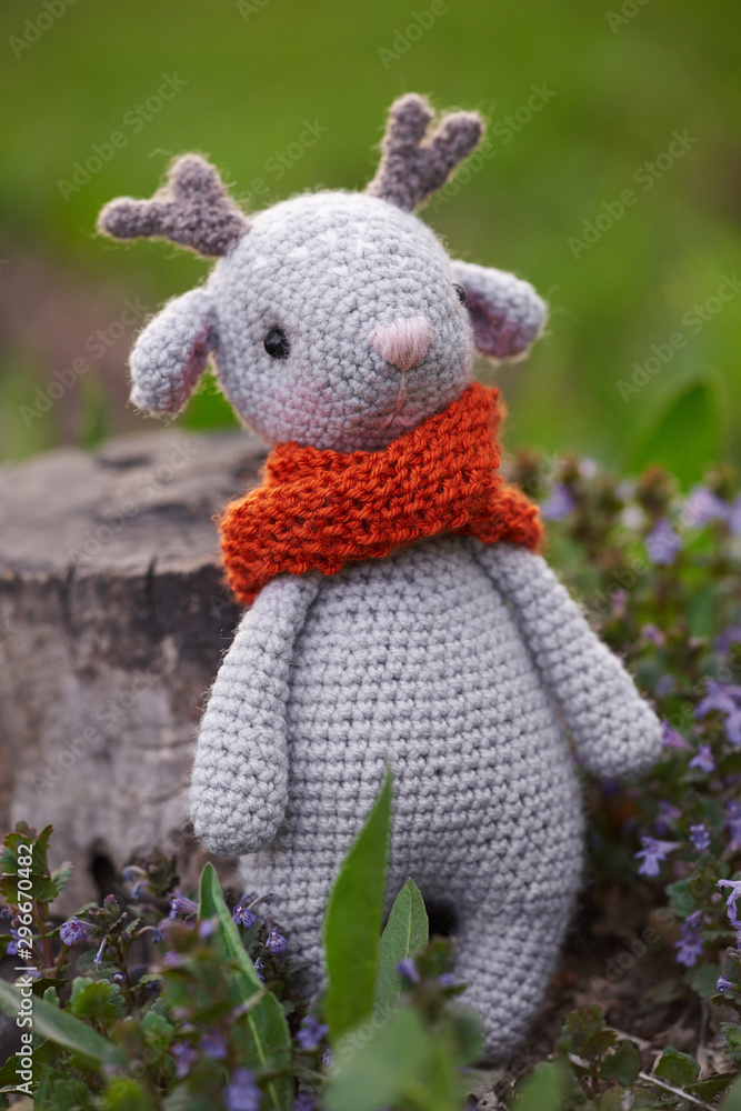Beautiful handmade soft toy fawn. Outdoor photography, grass and a small stump. Beautiful handmade soft toy fawn. Outdoor photography, grass and a small stump.