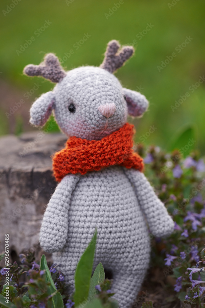 Beautiful handmade soft toy fawn. Outdoor photography, grass and a small stump. Beautiful handmade soft toy fawn. Outdoor photography, grass and a small stump.