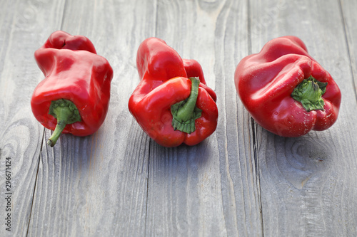 Red sweet pepper . ugly vegetables, three crooked peppers, on a gray woody background.