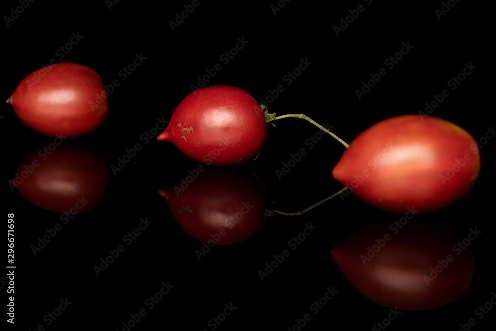 Group of three whole fresh tomato de barao diagonal isolated on black glass Group of three whole fresh tomato de barao diagonal isolated on black glass
