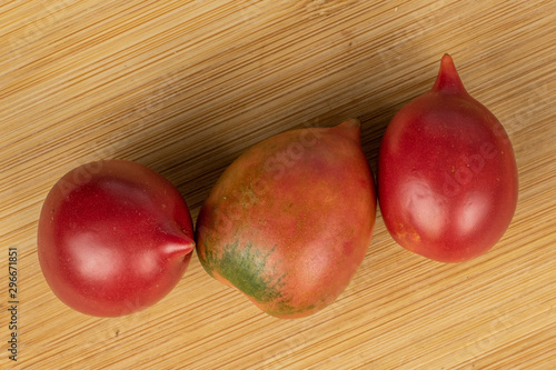 Group of three whole fresh tomato de barao flatlay on light wood photo