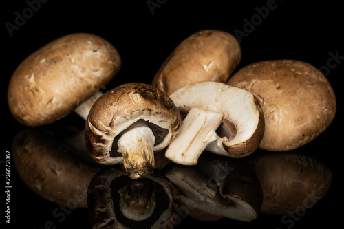 Group of four whole one half of fresh brown mushroom champignon isolated on black glass