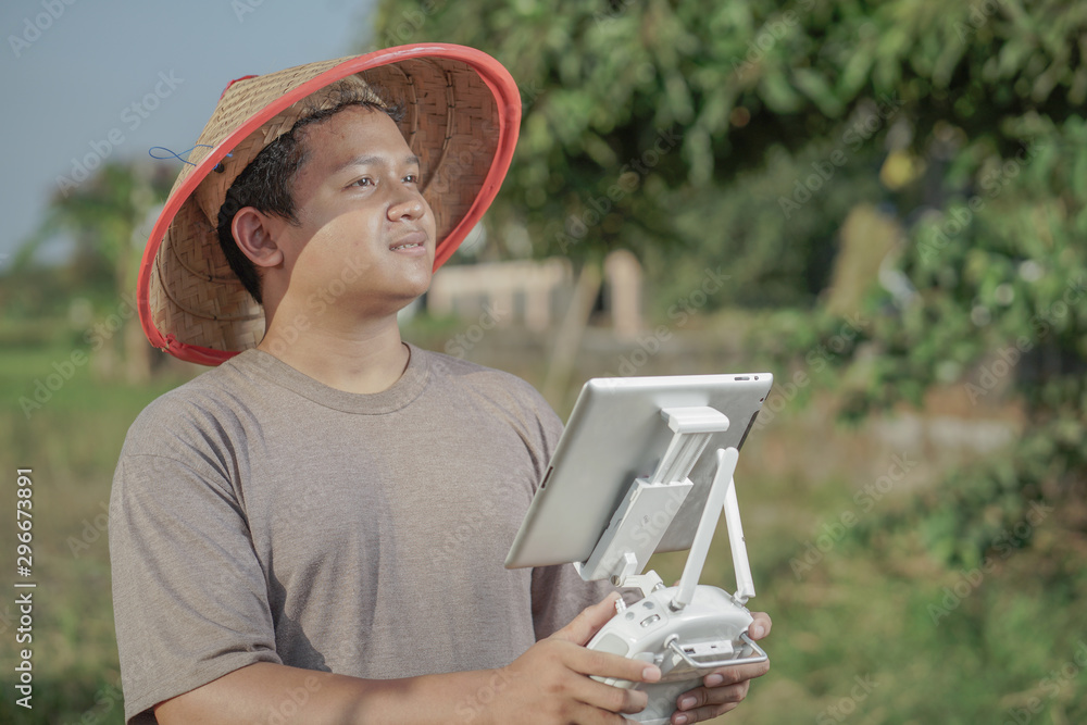 Fototapeta premium Asian farmers oversee his fields with sophisticated technology