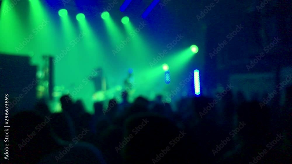 Blurred: rock concert in the club, green lights on stage, view from the back of the audience Blurred: rock concert in the club, green lights on stage, view from the back of the audience