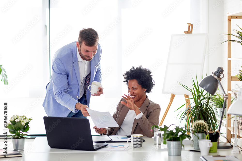 Two business people work in office together with laptop in front