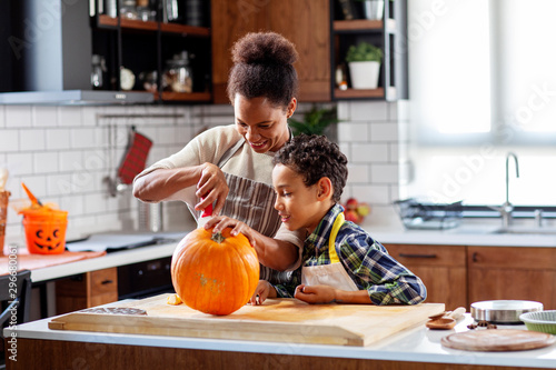 Mother with his son prepare pumpkin for halloween in the kitchen