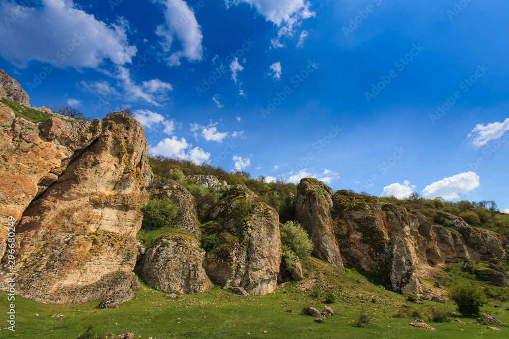 Beautiful rock formations in a canyon in Romania, on a summer day, profiled on deep blue sky with cumulus clouds