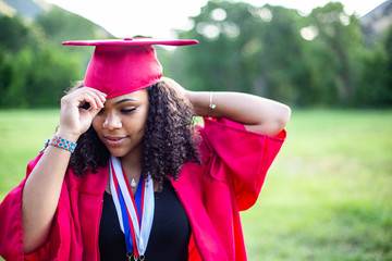 Candid Portrait of a beautiful multiethnic woman putting on her graduation cap and gown. Selective focus on her beautiful face