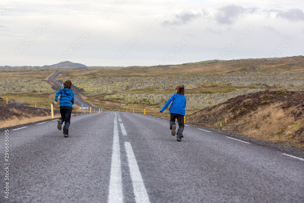 Kids running on an empty road in beautiful nature in Snaefellsjokull National Park in Iceland, autumntime Kids running on an empty road in beautiful nature in Snaefellsjokull National Park in Iceland, autumntime