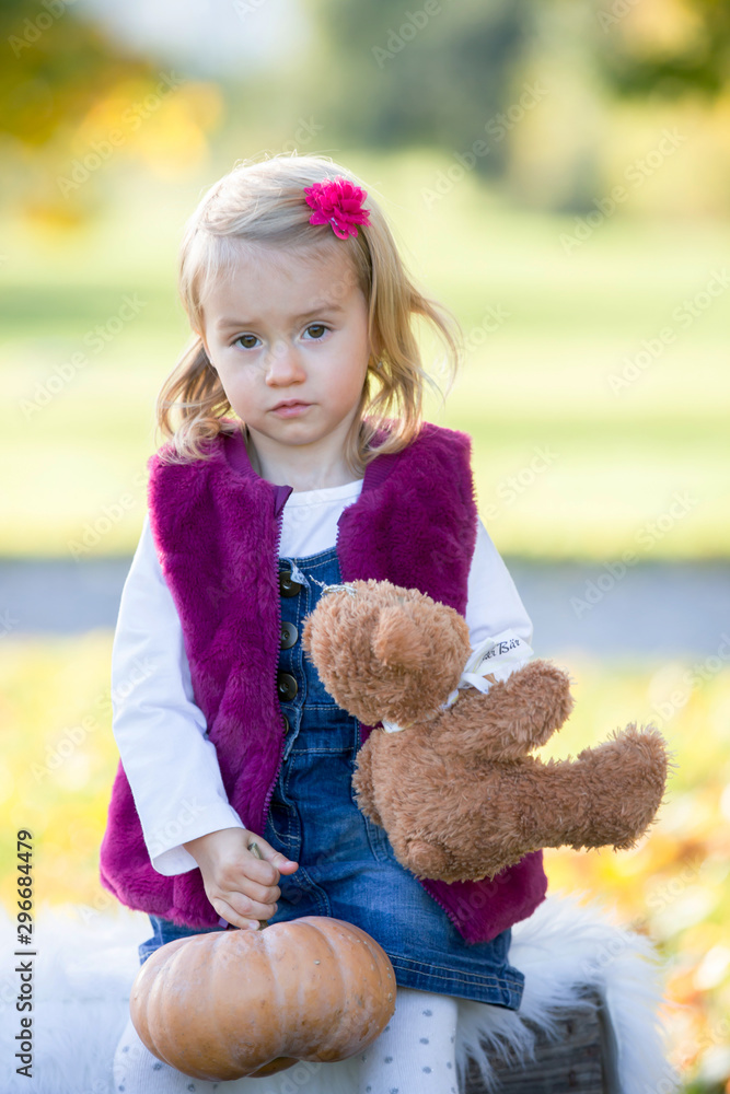 Sweet toddler baby girl, child, playing in the park with leaves on a sunny day Sweet toddler baby girl, child, playing in the park with leaves on a sunny day