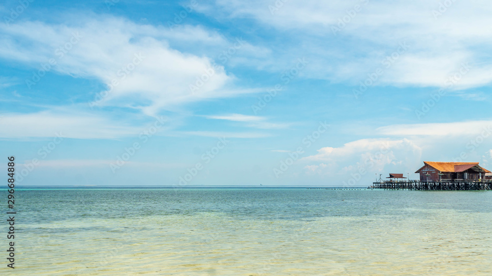 Beautiful view of crystal clear water, white sand, blue sky, traditional cottage, and wooden boat at Derawan Island, Indonesia Beautiful view of crystal clear water, white sand, blue sky, traditional cottage, and wooden boat at Derawan Island, Indonesia