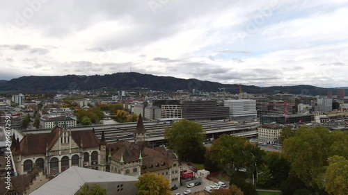 Right moving aerial truck shot of a main train station in Zurich, Switzwerland with a mountain in the background on an overcast day photo