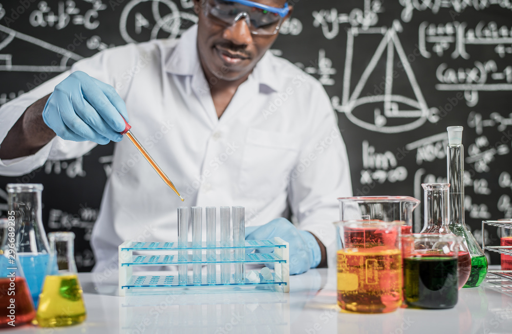 Scientists drop orange chemicals into the glass at the laboratory. Scientists drop orange chemicals into the glass at the laboratory.