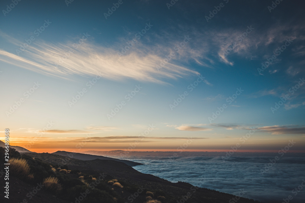 Sunset or sunrise beautiful landscape moment at the mountain - high peak vulcan and coloured sunlight in background - sea of clouds on the side - beauty of outdoor nature
