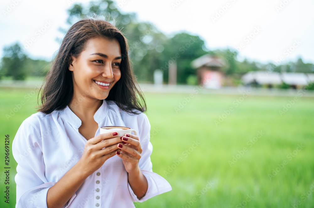 That woman stood happily drinking coffee on the meadow. That woman stood happily drinking coffee on the meadow.