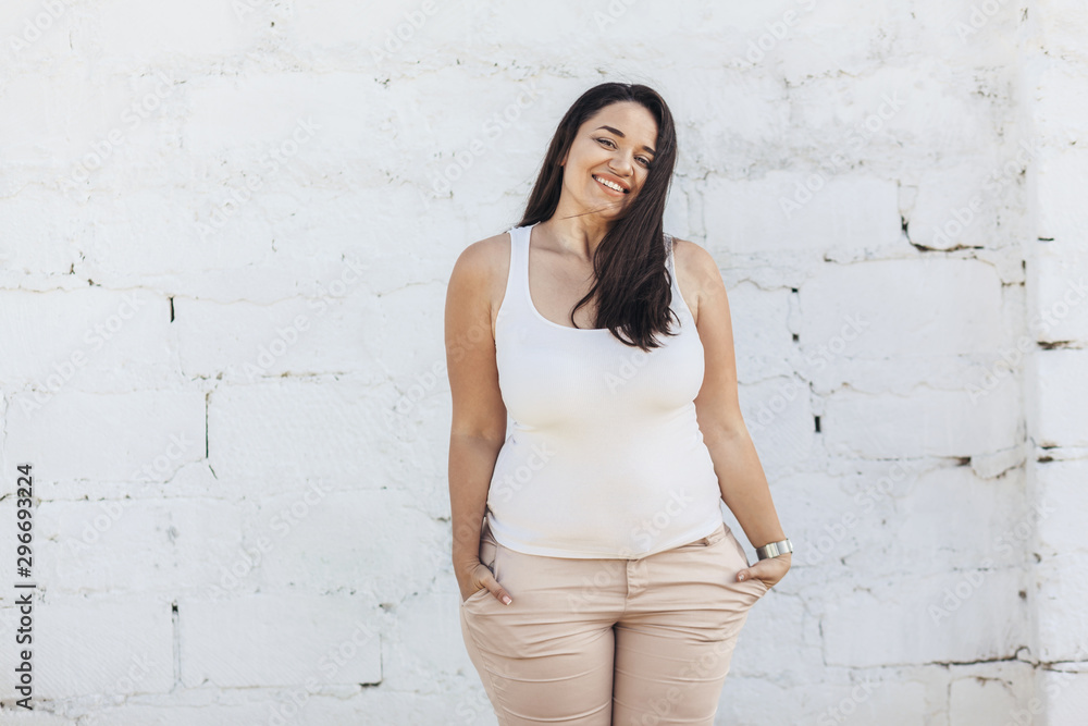 Plus size model dressed in white shirt posing over brick wall Plus size model dressed in white shirt posing over brick wall