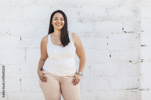 Foto Plus size model dressed in white shirt posing over brick wall
