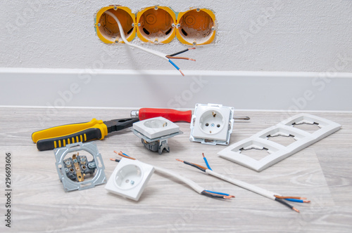 Sockets and cable in the wall, lying pliers on the floor, a screwdriver, sockets.