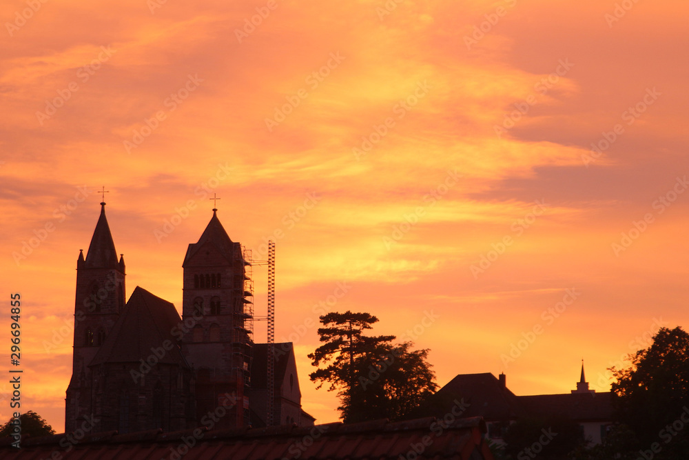 Church on hill with scaffolding due to restoration under orange evening  sky (Breisach, Baden, Germany)