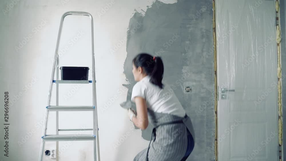 Woman worker using a spatula painting walls in the apartment or house. Woman worker using a spatula painting walls in the apartment or house.