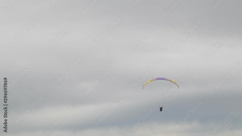 telephoto shot of a single paraglider flying in the distance during overcast day telephoto shot of a single paraglider flying in the distance during overcast day